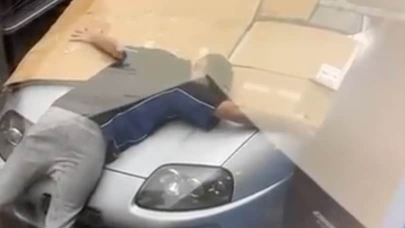 Un uomo protegge la sua Toyota dalla grandine